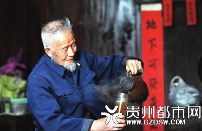 侗族老人肖元凯把茶水熬好后，倒进玻璃杯里喝