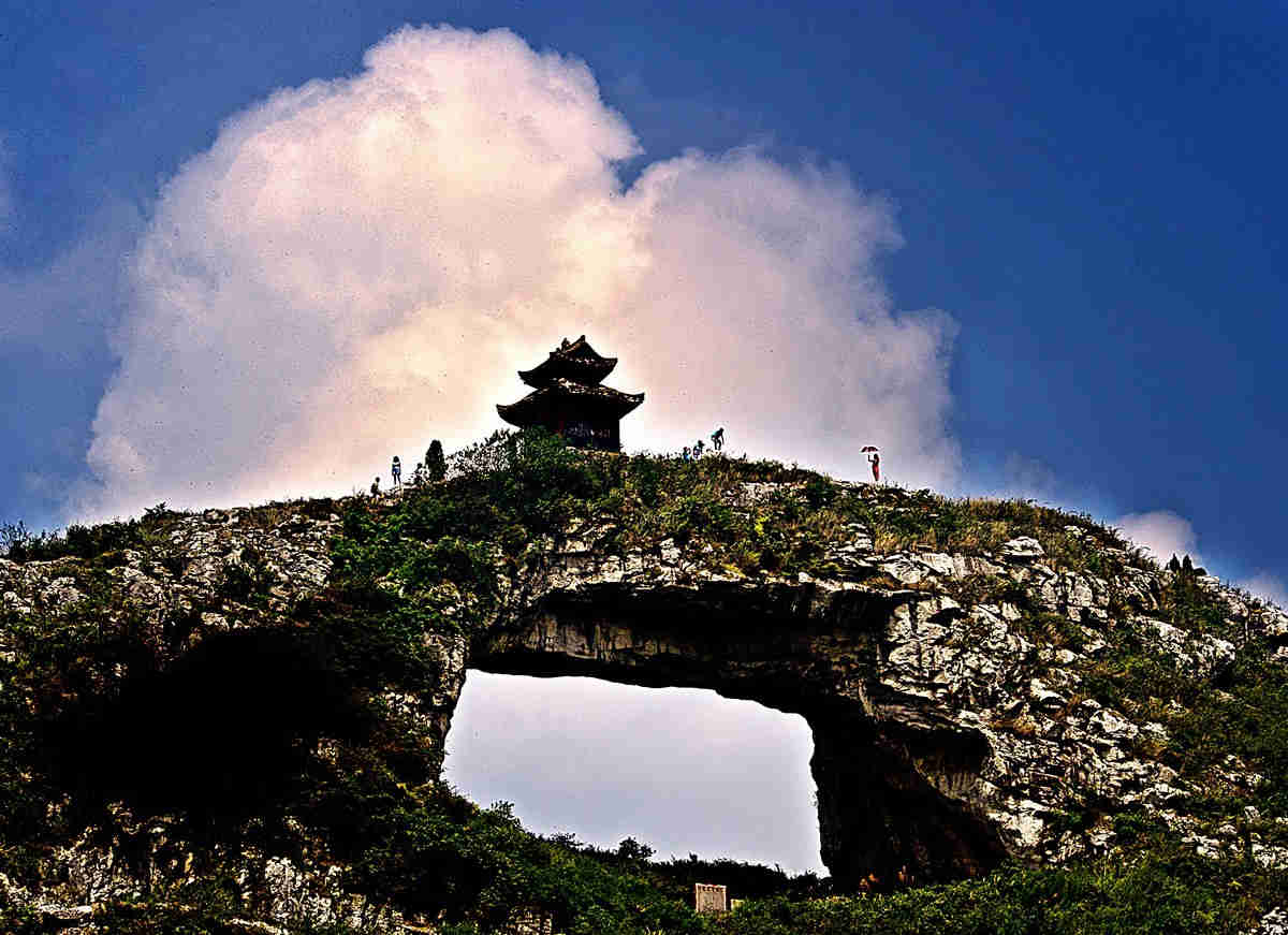 游人在欣赏蓝天白云下的瓮安仙桥山景色
